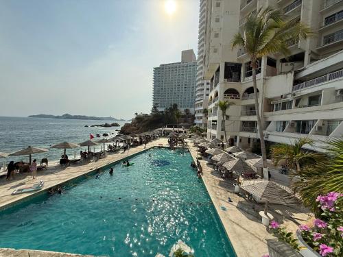 a swimming pool next to a beach with some buildings at Departamento nuevo con Vista al Mar! in Acapulco