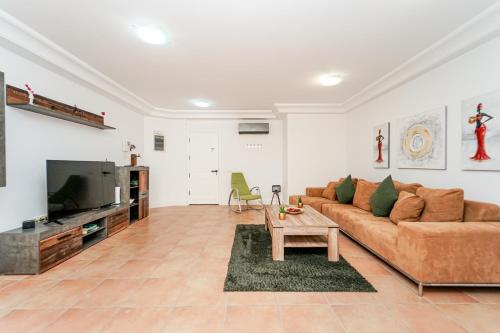 a living room with a couch and a tv at Villa Magnificent 5-star with sea view, jacuzzi and pool in Arguineguín