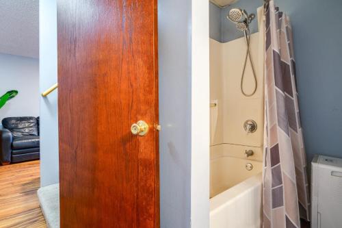 a bathroom with a wooden door next to a bath tub at Charming Basement Stay with Workspace AC & Fire Pit in North Saint Paul