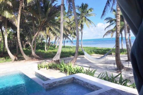 a resort with a hammock and a beach with palm trees at 4 Br Belize Beachfront Villa W Pool, Beach & Pier in Basil Jones