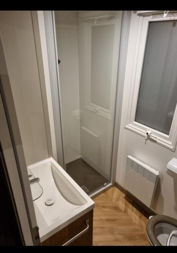 a white bathroom with a sink and a shower at mobil home in La Celle-sous-Gouzon