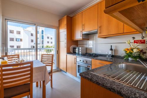 a kitchen with a sink and a table with a counter top at Apartamentos Turisticos Monte da Vinha II in Albufeira