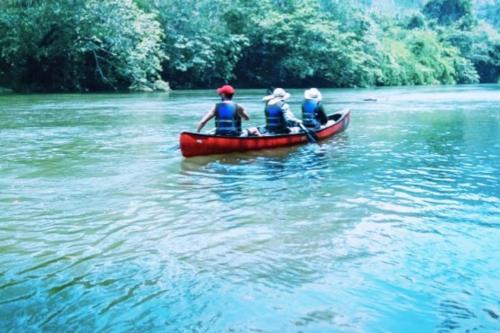 three people in a red canoe on a river at Private 2 Bdrm Home On 46 Acres Along Macal River in Duffy Bank