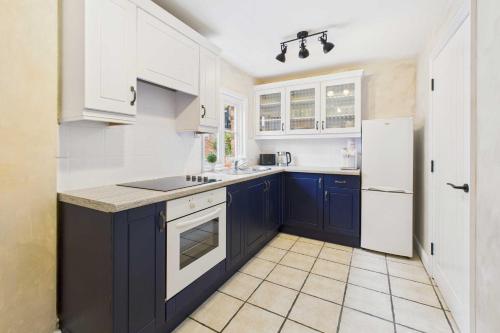 a kitchen with blue cabinets and a white refrigerator at Host & Stay - Dame Alice Street in Bedford