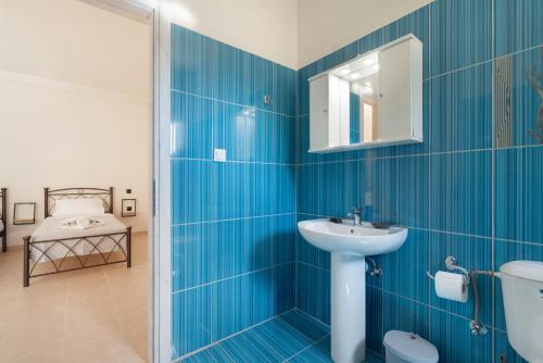 a blue tiled bathroom with a sink and a mirror at Panagis Apartments in Argostoli