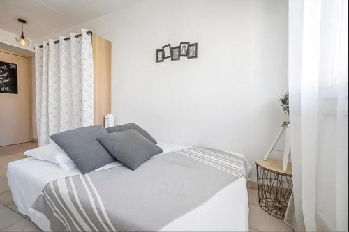 - une chambre blanche avec un lit et deux oreillers dans l'établissement Studio au Cœur d'Antigone, à Montpellier