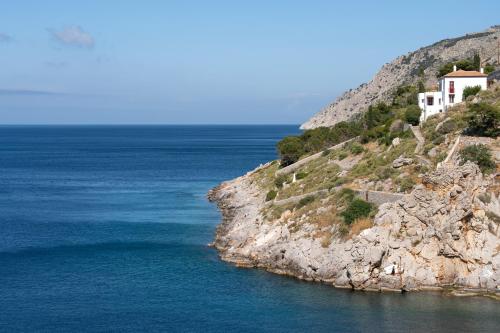 a house on a cliff next to the ocean at Aqua Vista Apartments with private seafront in Hydra