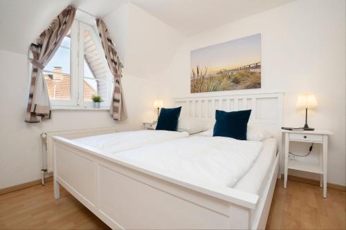 ein weißes Schlafzimmer mit einem weißen Bett und einem Fenster in der Unterkunft Appartementhausanlage Tiemann Donnerkeil in Kellenhusen