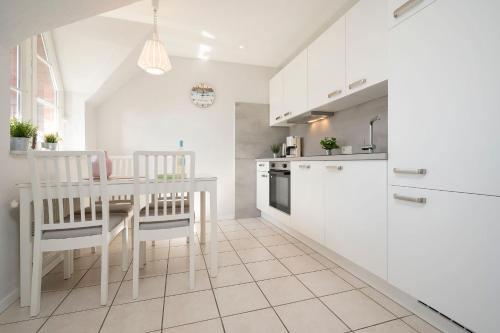eine Küche mit weißen Schränken und einem Tisch und Stühlen in der Unterkunft Appartementhausanlage Tiemann Donnerkeil in Kellenhusen