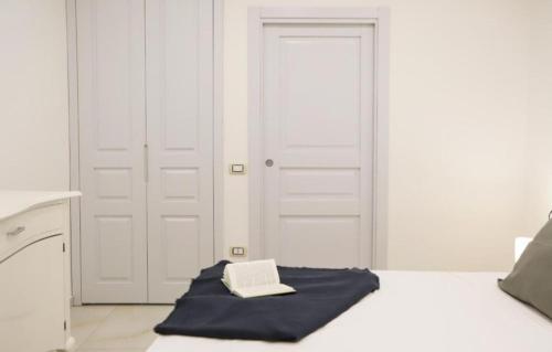 biała sypialnia z łóżkiem, na którym leży książka w obiekcie Monteoliveto Bed & Breakfast w mieście Neapol
