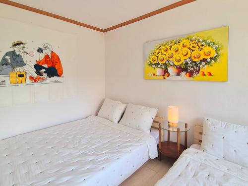 Un dormitorio blanco con una cama y un arreglo floral. en Happy Home Stay, en Seúl
