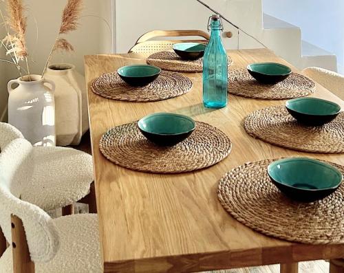 une table en bois avec des bols verts et une bouteille dans l'établissement Le Nid des Salants, à Loix