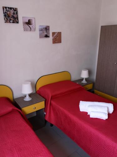 a room with two beds with red sheets and two lamps at Villa Leuka San Lorenzo in San Lorenzo