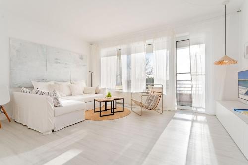 a white living room with a white couch and a table at Auszeit am Meer in Lemkenhafen auf Fehmarn