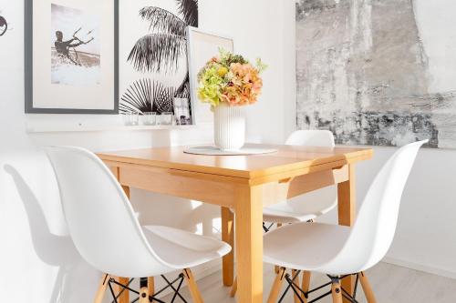 a dining room table with white chairs and a vase of flowers at Auszeit am Meer in Lemkenhafen auf Fehmarn