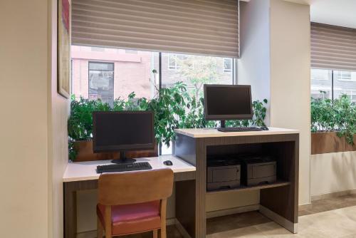 a computer desk with two monitors and a chair at Candlewood Suites NYC -Times Square by IHG in New York
