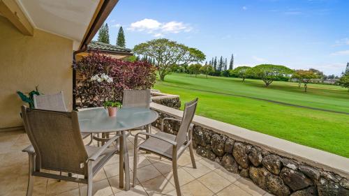a patio with a table and chairs and a green field at Kapalua Golf Villa 15P78 in Kapalua