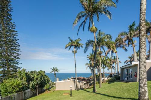 a house with palm trees in front of the ocean at Chakas Rock Chalets 15 in Ballito