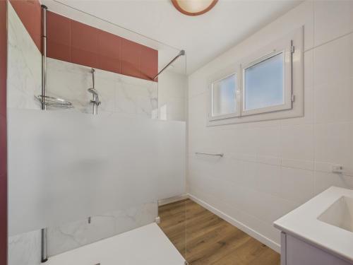 ein weißes Badezimmer mit Waschbecken und Fenster in der Unterkunft Maison de vacances à Saint Hilaire de Riez in Saint-Hilaire-de-Riez