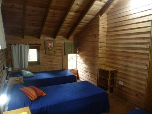 a room with two beds in a wooden cabin at Cabaña Kultrum Mar Azul in Mar Azul
