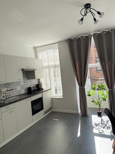 a kitchen with white cabinets and a window at EMM Guesthouse in Ypres