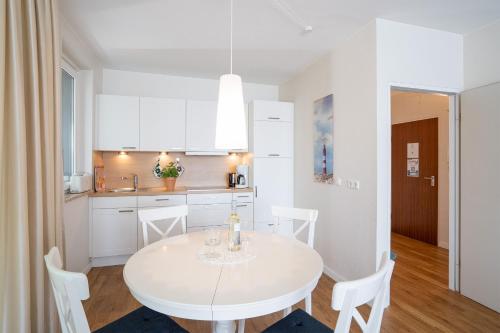 沙博伊茨Haus Meeresstrand Buddelschiff的白色的厨房，配有白色的桌子和椅子