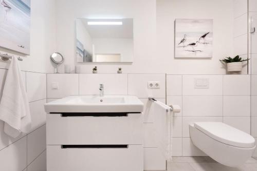 a white bathroom with a sink and a toilet at Viermaster Störtebeker in Kellenhusen