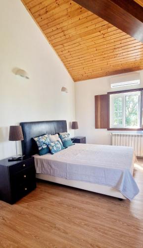 a bedroom with a large bed and a wooden ceiling at Cerca Velha Alentejo House in Cercal