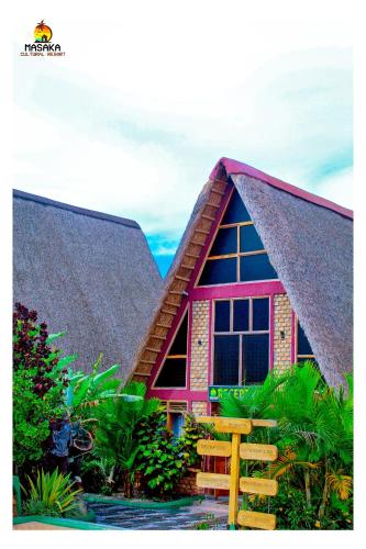 a house with a large window and a roof at Masaka Cultural Resort in Masaka