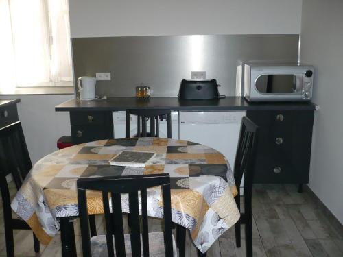 une cuisine avec une table avec des chaises et un micro-ondes dans l'établissement Gite La Fontaine Proche route des vins de Côte d'Or, Circuit Prenois, à Vielmoulin