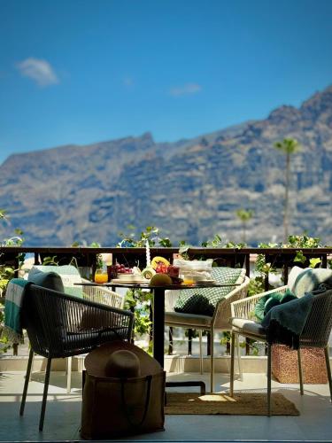 a table and chairs on a patio with a mountain at YOSO Tenerife in Acantilado de los Gigantes
