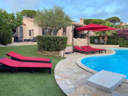 - une piscine avec des chaises longues rouges à côté d'une maison dans l'établissement Vivre Sainte-Maxime à pieds, à Sainte-Maxime