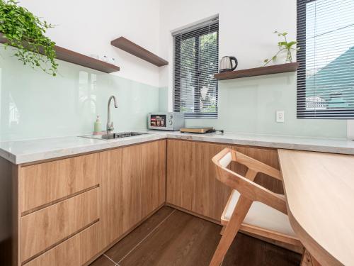 a kitchen with wooden cabinets and a wooden chair at Kim Apartment - Cozy 1BR for Couples in Thảo Điền - Yellow in Ho Chi Minh City