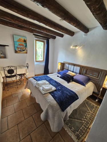 une chambre avec un grand lit et un bureau dans l'établissement Le Moulin du Temps -chambres et lounge bar au bord de la rivière, à Corbés