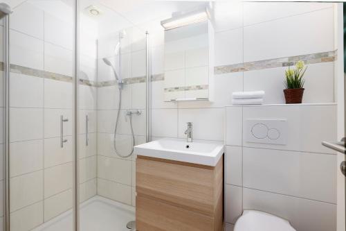 a white bathroom with a shower and a sink at Lütt Drosselhörn 1 in Laboe