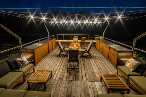 a deck with a table and chairs and lights at Water Hideout - Floating Villas in Wild Nature in Nowawieś Zbąska