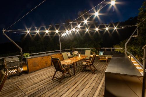 a deck with a table and chairs and lights at Water Hideout - Floating Villas in Wild Nature in Nowawieś Zbąska