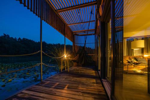a wooden porch with a view of the ocean at night at Water Hideout - Floating Villas in Wild Nature in Nowawieś Zbąska