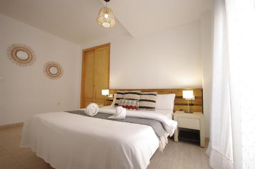 une chambre avec un grand lit blanc et deux lampes dans l'établissement Livingtarifa Apartamento Blue II, à Tarifa