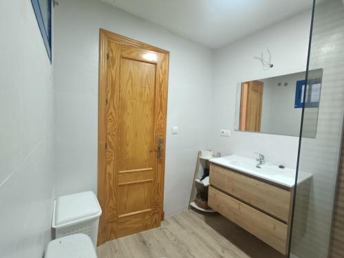La salle de bains est pourvue d'un lavabo et d'une porte en bois. dans l'établissement Livingtarifa Apartamento Blue II, à Tarifa
