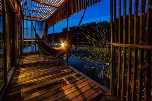 a hammock on a deck with a view of the water at Water Hideout - Floating Villas in Wild Nature in Nowawieś Zbąska