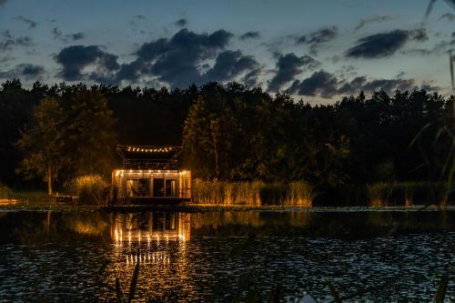 a small house in the middle of a lake at night at Water Hideout - Floating Villas in Wild Nature in Nowawieś Zbąska