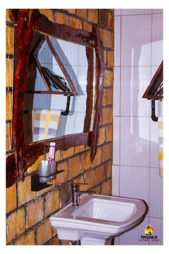 a bathroom with a sink and a mirror at Masaka Cultural Resort in Masaka