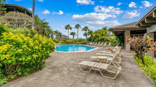 a couple laying on lounge chairs next to a swimming pool at Kapalua Ridge Villa 1721 in Kapalua