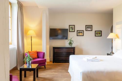 a hotel room with a bed and a purple chair at Le Manoir du Golf in Publier