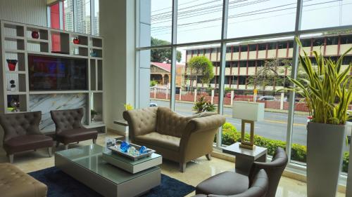 a living room with chairs and a table and windows at Ramada Plaza by Wyndham Panama Punta Pacifica in Panama City