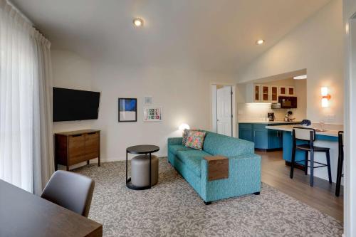 a living room with a blue couch and a kitchen at Sonesta ES Suites Sunnyvale in Sunnyvale
