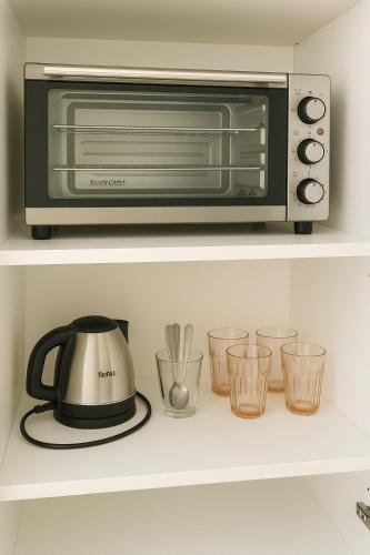 un four grille-pain sur une étagère avec des verres dans l'établissement Studio chic à 200 m du Palais des Festivals, au cœur du shopping Cannois, à Cannes