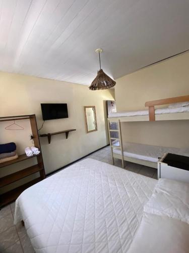 a bedroom with two bunk beds and a tv at Pousada Maré Alta - Maresias - 350mt da praia in Maresias