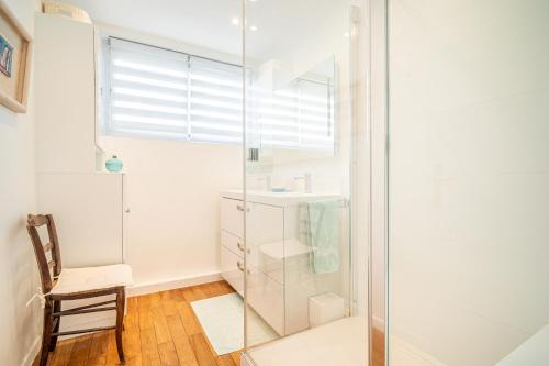 La salle de bains est pourvue d'une douche en verre et d'une chaise. dans l'établissement Lovely apartment with view, à Paris